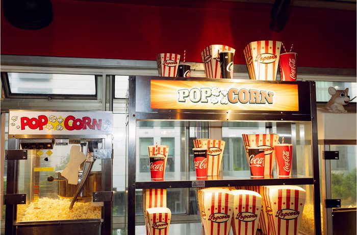Popcorn machine and display with striped popcorn buckets and Coca-Cola cups. Bright, fun atmosphere, evoking a cinema or carnival vibe.
